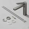 A faucet and its installation parts are laid out on a light gray surface. Voir les images du produit