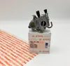 A Stihl carburetor is placed on its original packaging box, with a patterned Stihl paper roll in the foreground. Produktbild-Vorschau