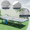 A camping cot with a thick mattress pad is set up on a grassy lawn, with close-up insets highlighting product features. Podgląd zdjęcia produktu