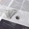 A close-up shot of a silver letter 'V' shaped hook and a metal eyelet, placed on top of a book with text. Produktbild-Vorschau
