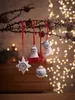Christmas ornaments hanging from a branch with bokeh lights in the background. Produktbild-Vorschau