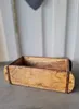 A wooden box with metal accents sits on a gray surface in front of a white and gray background. Podgląd zdjęcia produktu