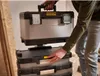 A person is shown stacking toolboxes. Voir les images du produit