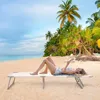 A woman is relaxing on a portable beach lounger on a sandy beach, reading a book. Palm trees and the ocean are in the background. Produktbild-Vorschau