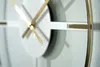 A close-up shot of a modern wall clock with gold hands and accents against a light background. Náhled obrázku produktu