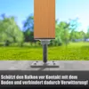 A close-up of a wooden post base with a metal adjustable support, set against a blurred background of grass and trees. Produktbild-Vorschau