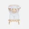 A white plush sheep toy sitting on a small wooden stool, presented against a plain white background. Produktbild-Vorschau
