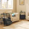 Two black bedside tables with drawers and charging ports are placed next to beige armchairs in a living room setting. Produktbild-Vorschau