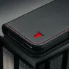 Close-up of a black leather phone case with red stitching and a red bull logo. Produktbild-Vorschau