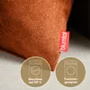 A close-up of an orange chenille cushion with care instruction icons and a brand tag. Anteprima dell’immagine prodotto