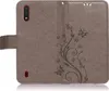 A brown flip case for a Samsung Galaxy A01 phone, decorated with a floral and butterfly pattern. Produktbild-Vorschau