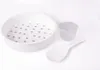A white steamer basket, a small gray measuring cup, and a white rice paddle are arranged on a white background. Anteprima dell’immagine prodotto