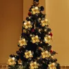 A decorated Christmas tree with golden poinsettia ornaments and lights. Produktbild-Vorschau