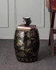 A black ceramic garden stool with gold dragon and shield motifs sits on a gray carpet. A book and a mug are placed on top of the stool. Anteprima dell’immagine prodotto