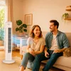 A couple relaxing on a couch in a living room with a tower fan. Produktbild-Vorschau