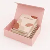 A pink box with a lid open, containing a stack of notebooks with a patterned cover. Podgląd zdjęcia produktu