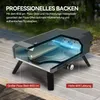 A pizza oven is shown on a wooden table outdoors, with text overlays highlighting its features. Produktbild-Vorschau