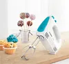 A white and teal Bosch hand mixer is shown on a wooden surface next to cupcakes and cake pops. Náhled obrázku produktu