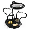 A black helping hands tool with a magnifying glass and LED light, used for soldering and electronics work. Produktbild-Vorschau