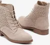 A pair of beige, laser-cut ankle boots are shown against a white background. Voir les images du produit