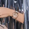A close-up shot of a person's wrist wearing a rose gold G-Shock watch against a shimmering silver background. Voir les images du produit