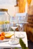 Two wine glasses on a table with a pitcher of infused water and fruit. Produktbild-Vorschau