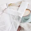 A close-up of a sheer curtain with embroidered details, placed over a book and a cup of coffee. Produktbild-Vorschau