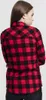 A woman is shown from the back wearing a red and black checkered flannel shirt. Náhled obrázku produktu