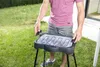 A person is setting up an electric grill in a grassy outdoor area. Náhled obrázku produktu