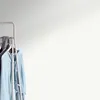 A clothing rack with several garments hanging on it, against a plain background. Náhľad obrázku produktu