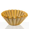 A brown paper coffee filter sits on a reflective white surface against a white background. Produktbild-Vorschau