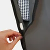 A hand is holding a sewing needle close to a zipper on a garment bag. Inside the bag, a patterned fabric is visible. Produktbild-Vorschau