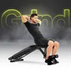 A man is performing sit-ups on an adjustable weight bench. The word "Grind" is displayed in large, neon yellow letters in the background. Produktbild-Vorschau
