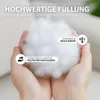 Hands holding a fluffy white filling material, with text overlays describing its qualities. Produktbild-Vorschau
