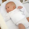 A baby lying in a crib. Anteprima dell’immagine prodotto