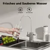 A hand is filling a glass with water from a filter faucet over a sink with fruit in a basket. Produktbild-Vorschau