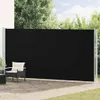 A black retractable side awning is installed on a patio, with a chair and a small table visible in the foreground. Voir les images du produit