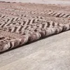 A close-up view of a textured rug with a geometric pattern, lying on a wooden floor. Produktbild-Vorschau