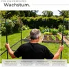 A man stands in front of a greenhouse structure in a garden. Produktbild-Vorschau