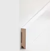 A close-up view of a white MDF baseboard profile against a white wall. Produktbild-Vorschau