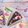A collection of triangular chocolate treats decorated with edible figures and sprinkles, arranged on a white plate. Anteprima dell’immagine prodotto