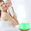 A woman is holding a baby while a green aroma diffuser is emitting mist in the foreground. Anteprima dell’immagine prodotto