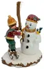 Ein Junge mit Schlittschuhen schmückt einen Schneemann mit einem Besen während ein kleiner Vogel auf dem Arm des Schneemanns sitzt und die Szene auf einer schneebedeckten Basis platziert ist Anteprima dell’immagine prodotto
