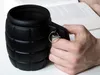 A hand holds a black grenade-shaped mug in front of an open book. Voir les images du produit