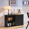 A black wooden sideboard cabinet with a lamp, dishes, and bottles on top, in a room setting. Produktbild-Vorschau