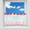 A short bistro curtain with a floral pattern hangs in a window, with a blue sky and clouds visible outside.