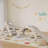 A children's indoor climbing structure with a slide, ramp, and arch, set up on a colorful play mat in a room. Produktbild-Vorschau