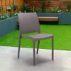 A taupe chair is placed on a patio in a garden setting with artificial grass and planters. Produktbild-Vorschau