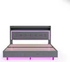 A grey upholstered bed frame with a headboard featuring LED lighting and a shelf, shown from the front on a white background. Podgląd zdjęcia produktu