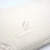 A close-up of a textured cream-colored pillow with a subtle cotton flower pattern. Produktbild-Vorschau